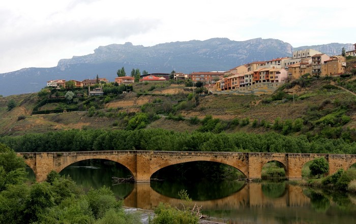 Stone bridge over a river with a town on a hill in Spain