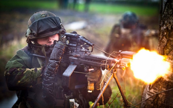 Soldier firing a machine gun during combat