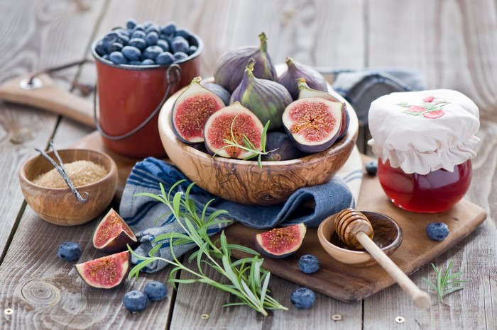 Figs, blueberries, honey, and sugar on a wooden table