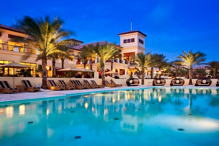 Resort with pool and palm trees at dusk