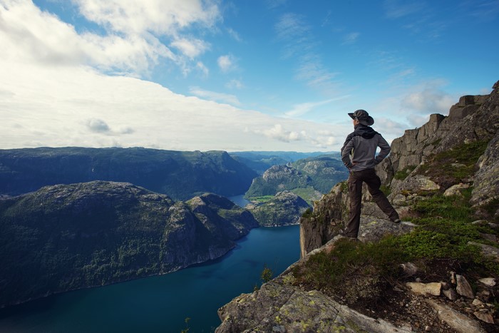 Man on cliff overlooking fjord scenery