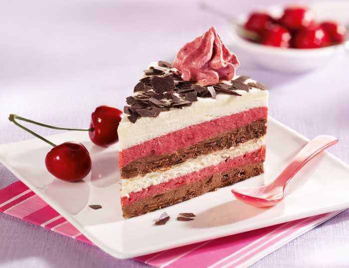 Slice of layered cake with cherries and chocolate shavings