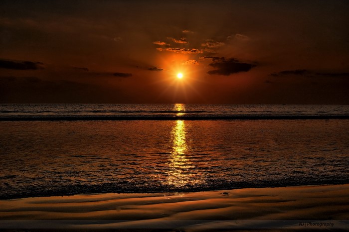 Sunset over the ocean with reflection on water