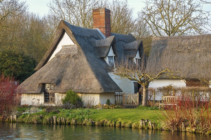 Thatched roof cottages by a river in East Bergholt, England