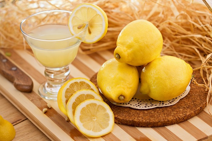 Fresh lemons and lemon juice on a wooden board
