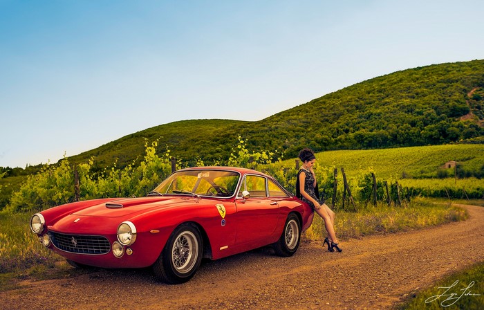 Woman leaning on a red Ferrari 250 GT in a vineyard