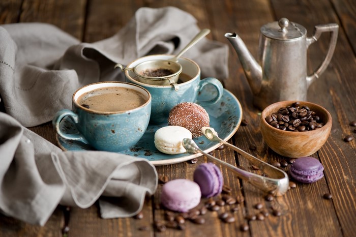 Coffee cups with macarons and coffee beans