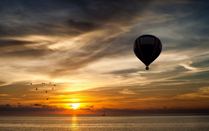 Hot air balloon over the ocean at sunset