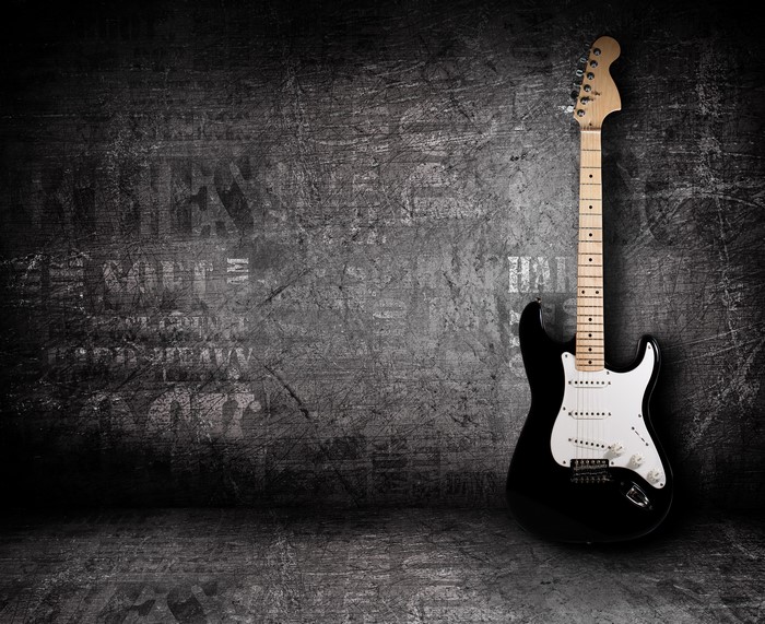 Black electric guitar against a grunge wall