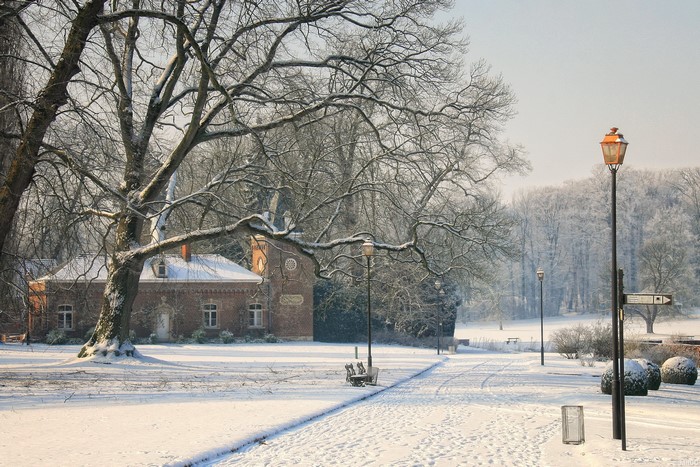 Winter scene in Meise, Belgium with a brick building and snow-covered trees