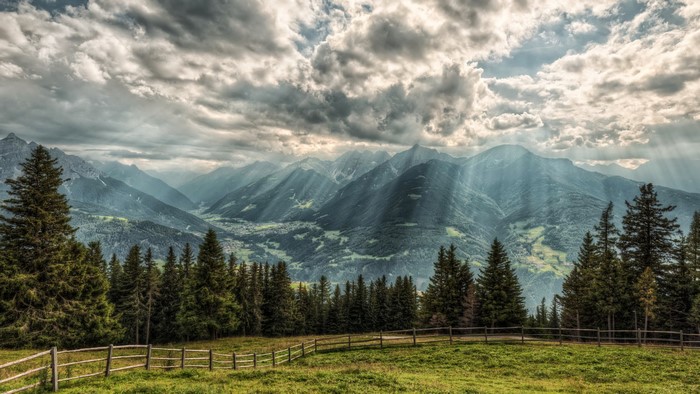 Sunbeams over Austrian Alps with a wooden fence