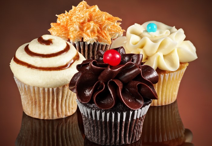 Four decorated cupcakes on a reflective surface