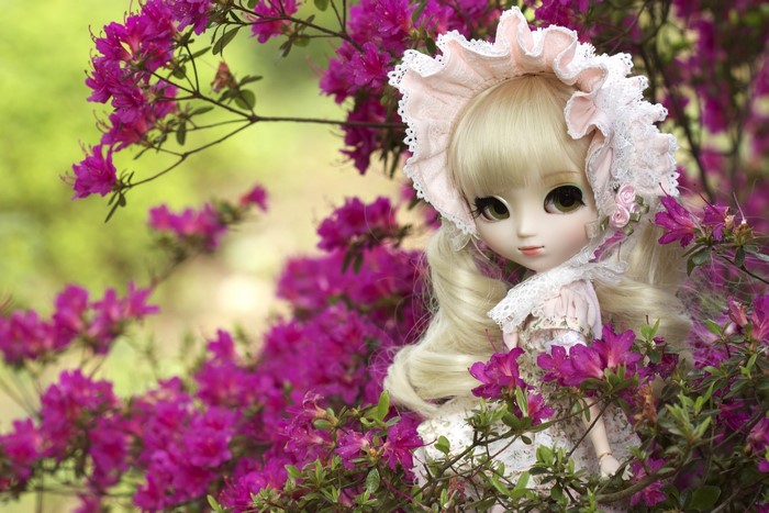 Doll with blonde hair among pink flowers