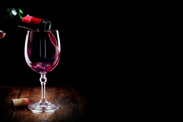 Red wine being poured into a glass on a wooden table