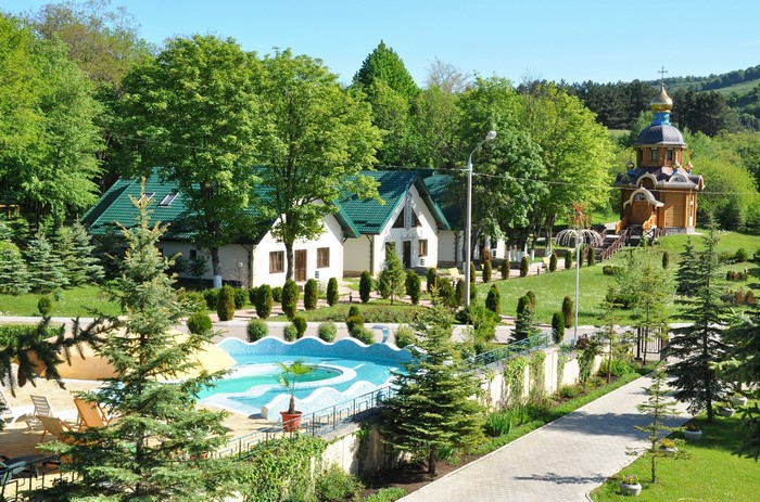 Houses and chapel in a green landscape with a pool