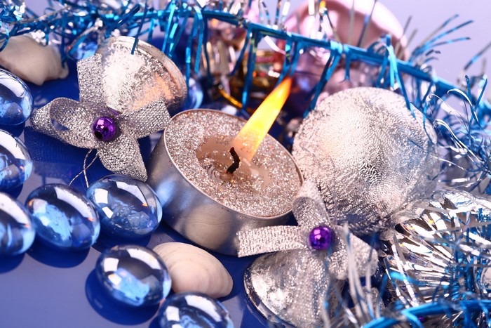 Close-up of a lit candle with Christmas ornaments