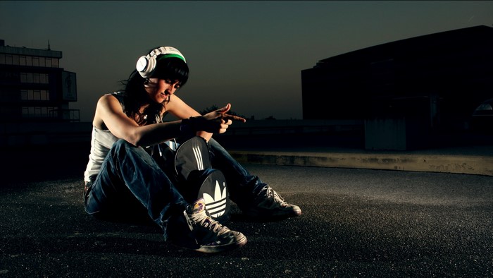 Girl with headphones and skateboard at night