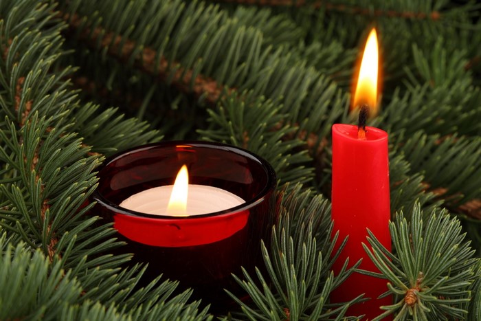 Two lit candles among pine branches