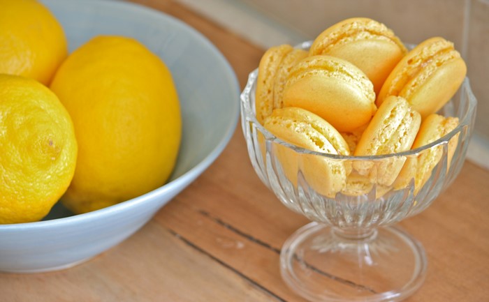Yellow macarons in a glass bowl with lemons