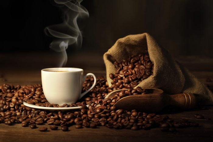 Steaming Coffee Cup with Roasted Beans and Burlap Sack