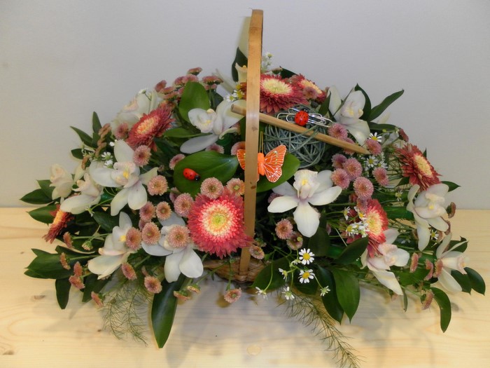 Flower arrangement in a wicker basket with ladybugs and butterflies