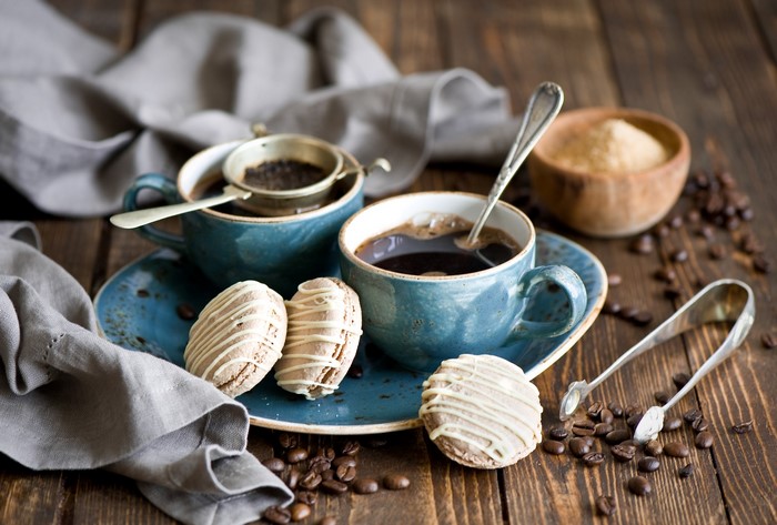 Two cups of coffee with macarons and sugar