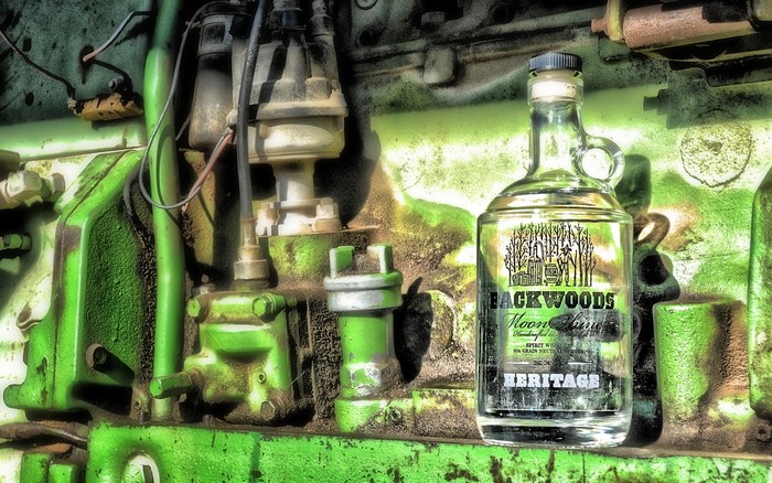Backwoods Heritage Moonshine bottle on tractor engine