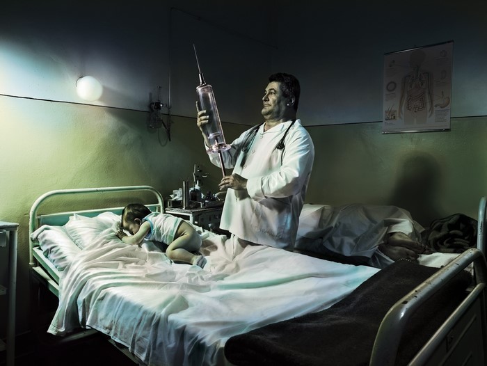 Doctor with giant syringe and baby in hospital room