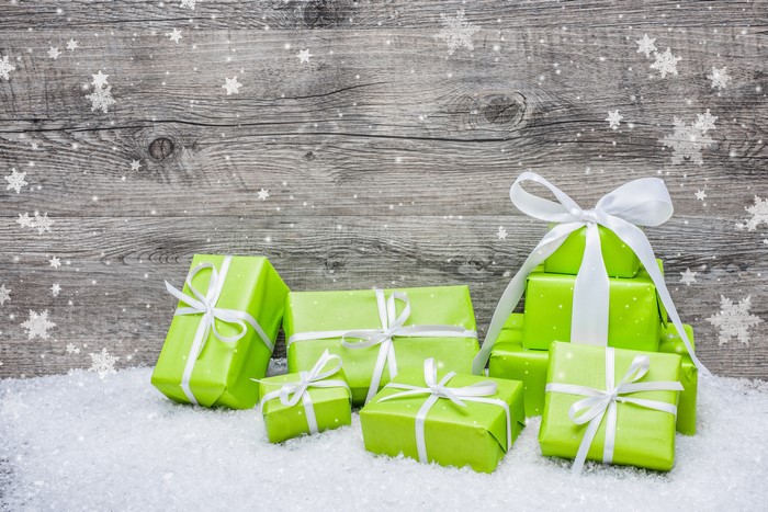 Christmas gifts wrapped in green paper with white ribbons on snow