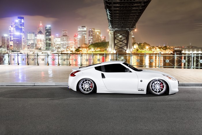 White Nissan 370Z parked by a bridge at night