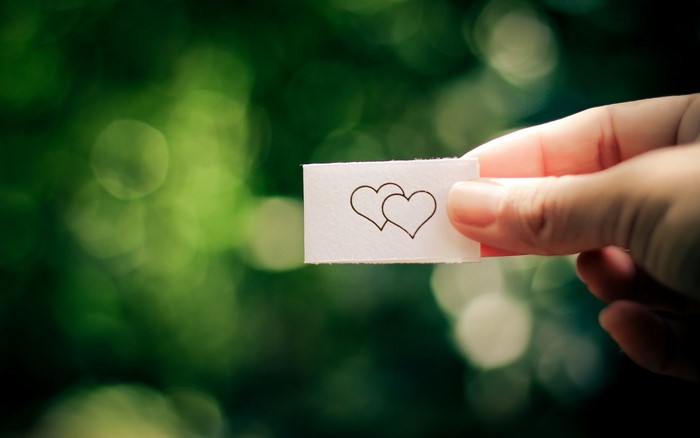 Hand holding paper with two hearts