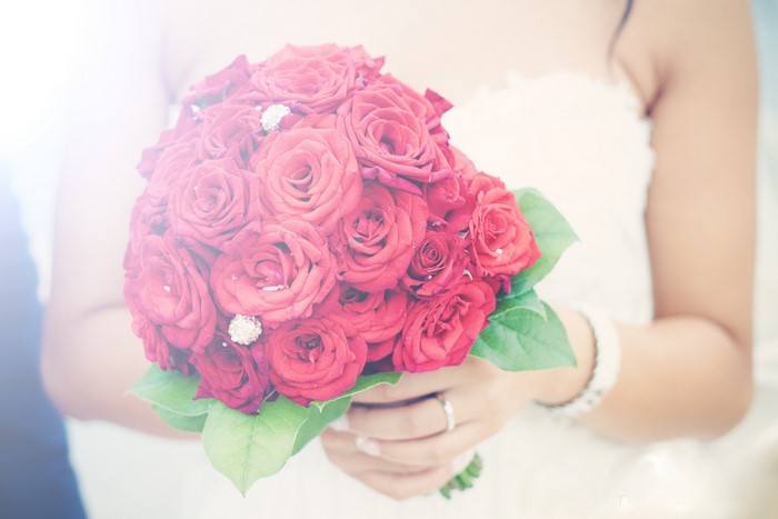 Bride holding red rose bouquet with diamond accents
