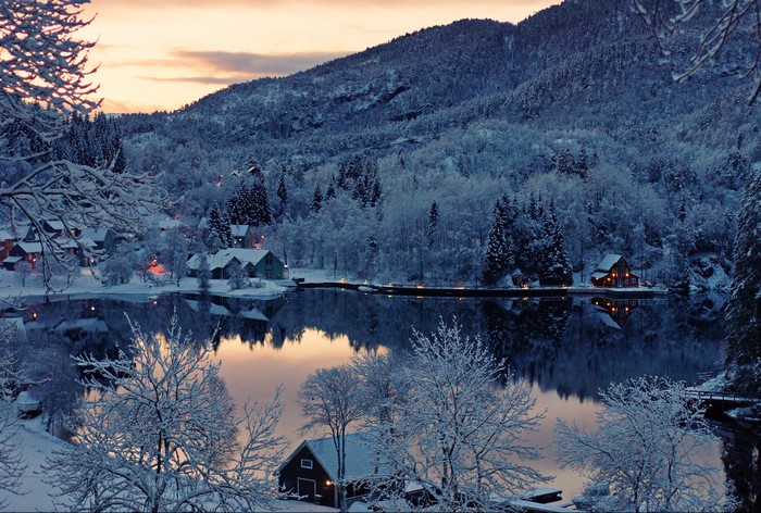 Winter scene with snow-covered houses by a lake in Finland
