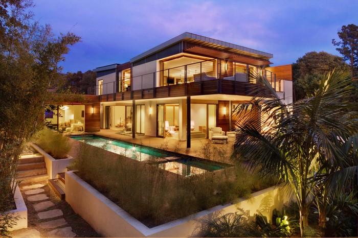 Modern multi-story house with swimming pool at dusk