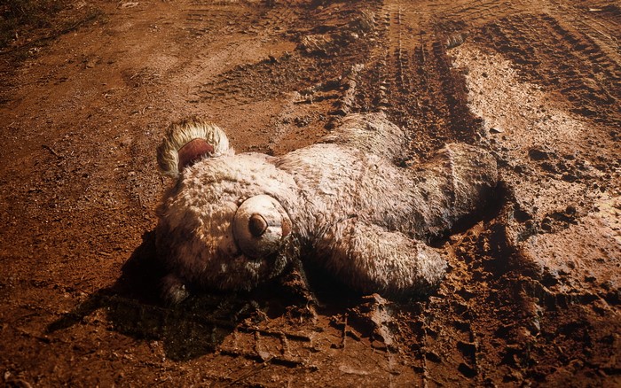A dirty teddy bear lying in mud