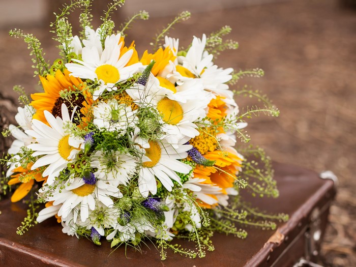 Bouquet of daisies and sunflowers on a suitcase