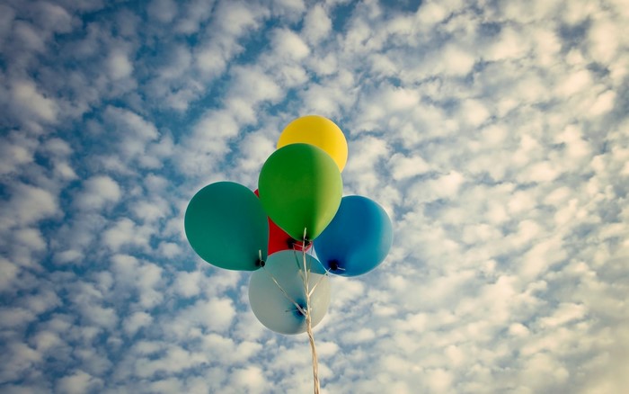 Colorful balloons floating in a cloudy sky