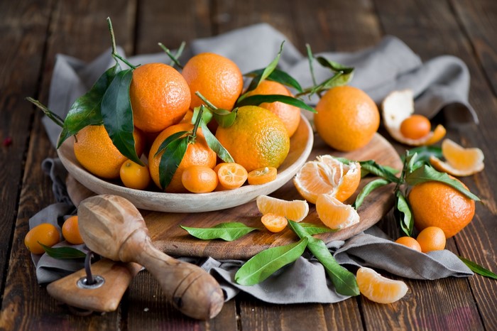 Mandarin oranges and kumquats in a bowl with a juicer