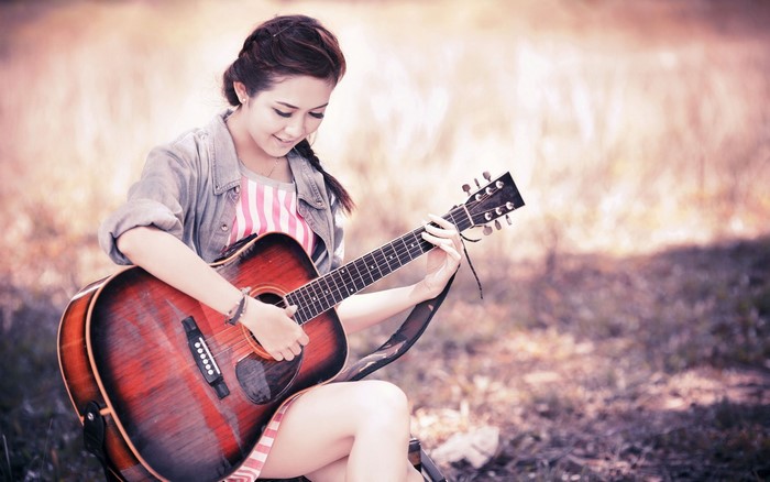 Asian girl playing guitar outdoors