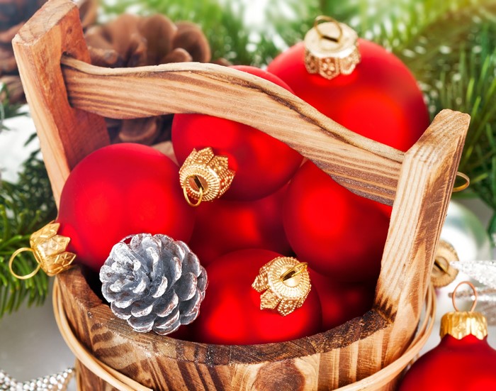 Christmas ornaments and pine cones in a wooden bucket