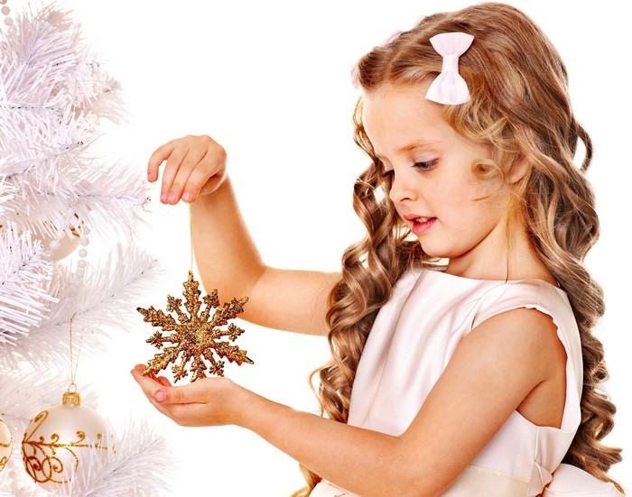 Little girl decorating Christmas tree with snowflake ornament