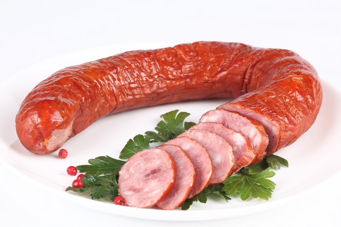 Sausage on a white plate with parsley and peppercorns