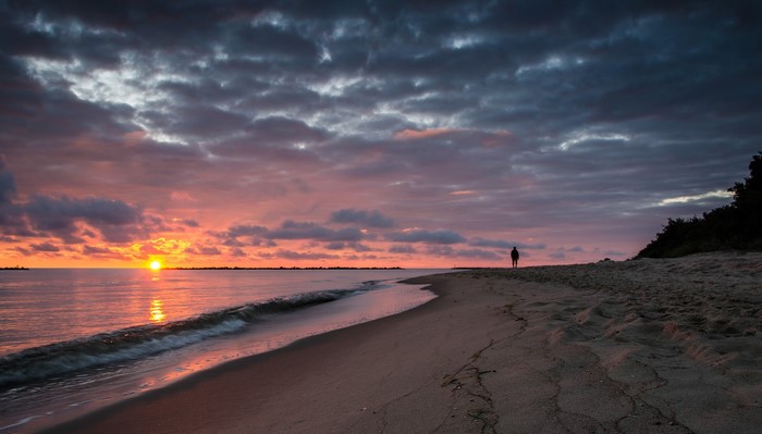 Sunset over the sea with a person on the beach