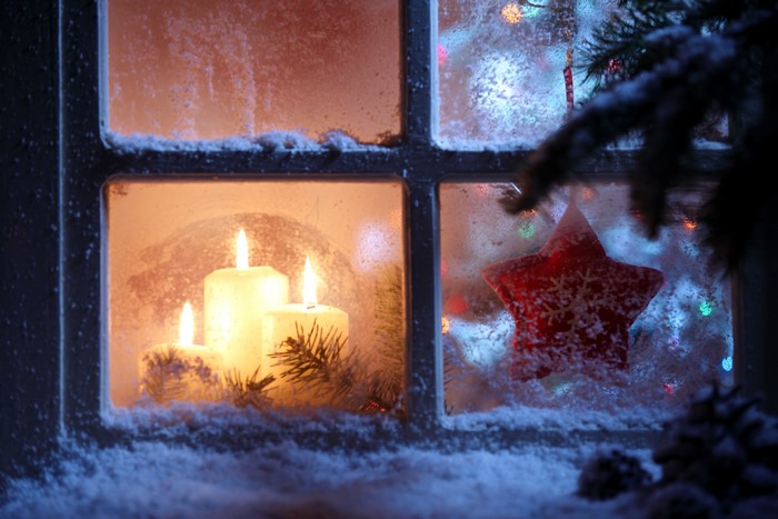 Christmas candles and star ornament on a snowy window