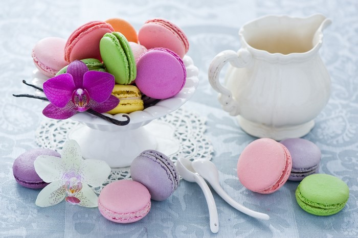 Colorful macarons on a cake stand with orchids and a pitcher