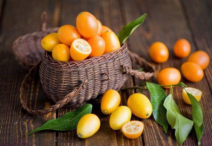 Kumquats in a wicker basket on a wooden table