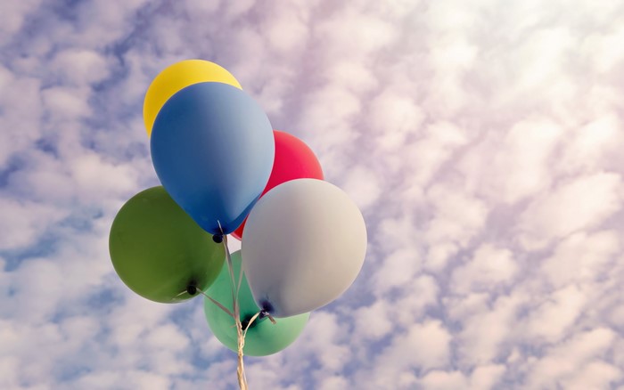 Colorful balloons floating in a cloudy sky