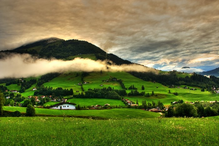 Green Mountainside Village with Foggy Clouds