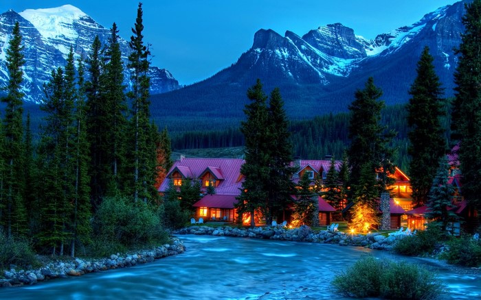 Mountain lodge by a river at dusk