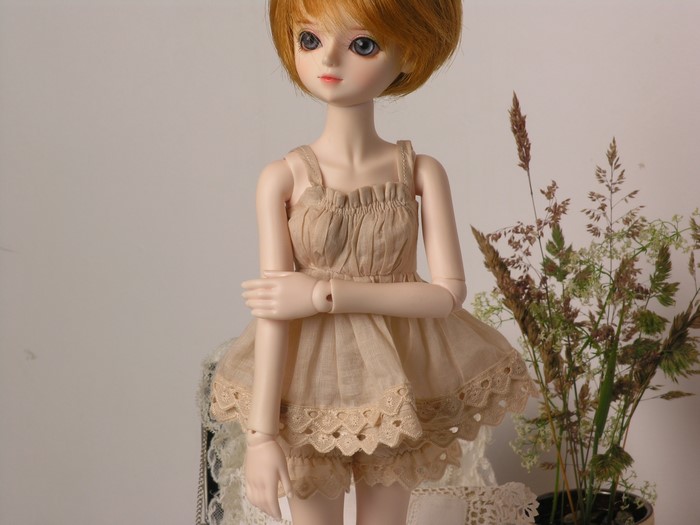 Doll wearing a beige dress with lace trim